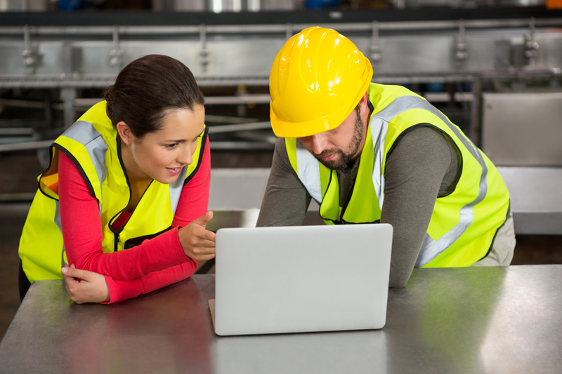 Operarios de almacén gestionando trabajo en ordenador.